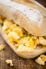 Wooden table with Scrambled Eggs on a bun (selective focus)