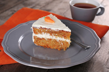 Piece of carrot cake with a cup of tea on wooden table