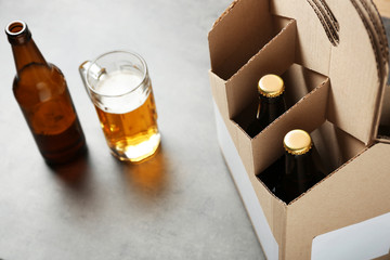 Paper beer package with mug on grey background