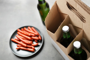 Paper beer package with sausages on grey background