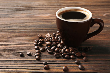 Cup of coffee with beans on wooden table