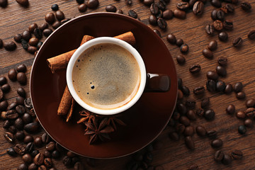 Cup of coffee with beans on wooden table