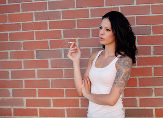 Rebel brunette woman with tight shirt smoking a cigarette