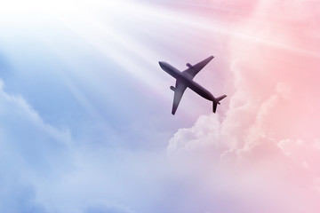 Airplane in the sky and colorful clouds in sunset bacground