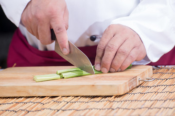 Chef slicing leak on wooden broad