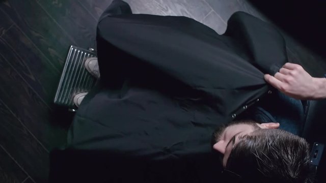 Top view of hairdresser covering his client with barber cloth and fastening it around his neck
