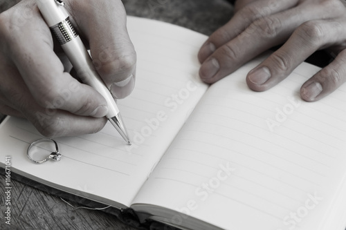 "Hand writing white pen notebook with diamond ring in memory" Stock