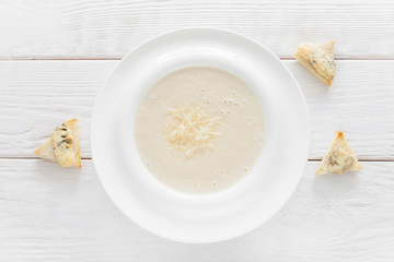 Cheese soup-puree with canape on white wooden background, flat lay. Homemade organic cream-soup with bruschetta slices