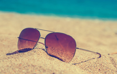 blurred abstract Fashion sunglass on the summer beach at ocean background , vintage filter , Summer vacation actually relaxing, summer concept , vocation time , summer background