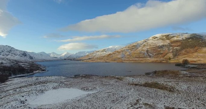 Aerial: Stunning view of Scottish lake in Highlands during winter, North Scotland