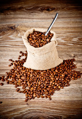 The sack of coffee beans on wooden background