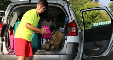 young boy with glasses loaded the luggage in the trunk