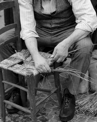 old man mender of chairs while repairing old wooden chair