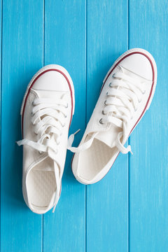 A pair of white canvas shoes on a blue wooden