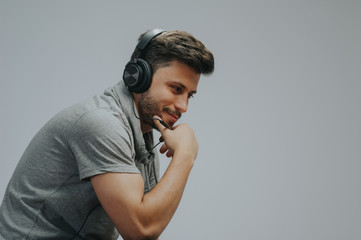Portrait of a young handsome man face smiling on a grayed background with headphones listening to music