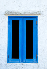 Window with blue shutters on a white wall. Window with closed shutters. Blue window in the wall of the house.
