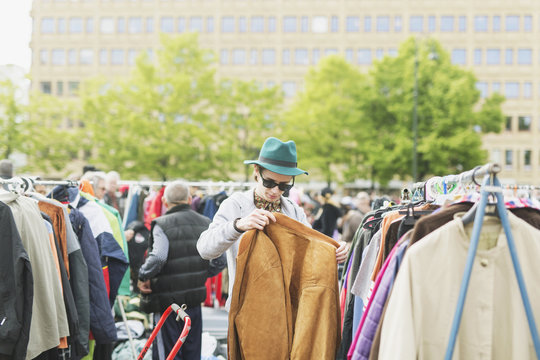 Young Man Holding Jacket While Shopping At Flea Market