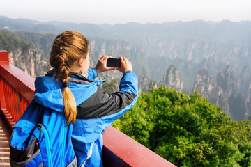 Naklejka premium Female tourist with smartphone taking photo of mountains