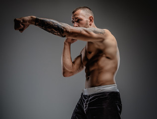 Tattooed fighter isolated on a grey background.