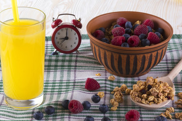 Muesli with fresh berries, orange juice and alarm clock.