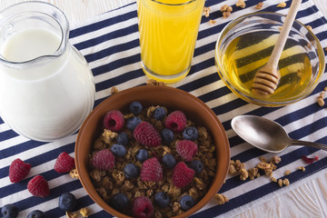 Muesli with fresh berries, honey, milk and orange juice.