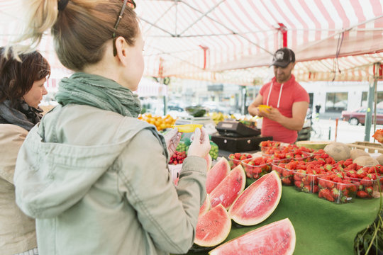 Mature woman tasting mango slice at fruit stall