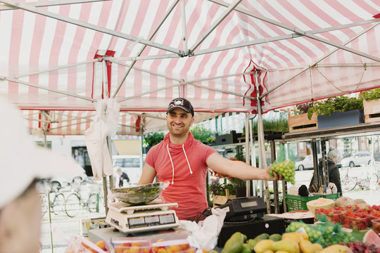 Happy male vendor selling fruits at market stall