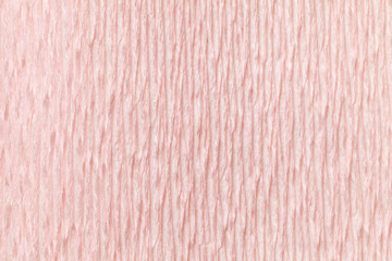 Textural light pink background of wavy corrugated paper, close-up.