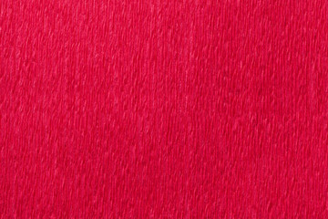 Textural bright red background of wavy corrugated paper, close-up.