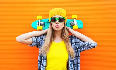 Poster Fashion pretty cool girl with skateboard over colorful orange ba © rohappy