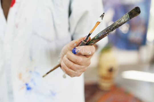 Midsection of female artist holding paintbrushes at art studio