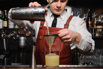 Fototapeta na wymiar Bartender pouring fresh cocktail in fancy glass