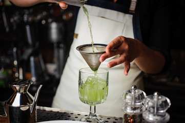 Bartender pouring fresh cocktail in fancy glass