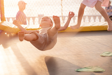children jumping on trampoline on coast - obrazy, fototapety, plakaty
