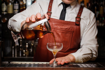 Bartender pouring fresh cocktail in fancy glass