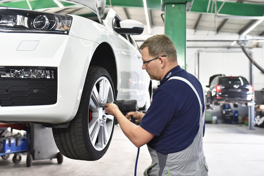 Reifenwechsel in einer Autowerkstatt durch Mechaniker // Changing tires in a garage by mechanics