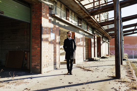 Lonely businessman in front of abandoned industrial building