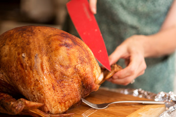 Woman carving a Thanksgiving turkey.