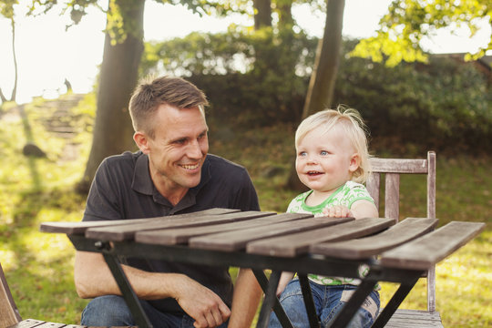 Father and daughter sitting at wooden table in garden