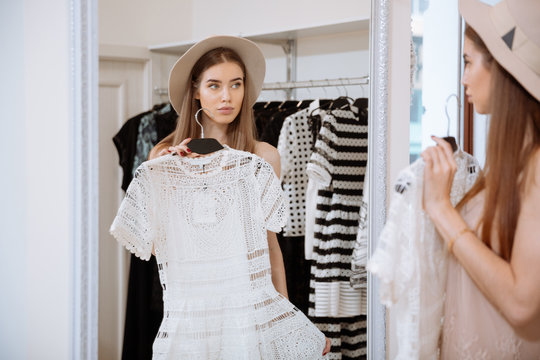 Attractive Young Woman Trying On Dress In Front Of Mirror