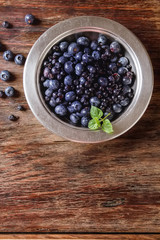 Blue ripe blueberries in a metal plate. wooden background. Top