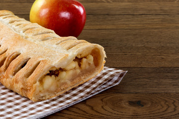 Apfelstrudel im Anschnitt auf karierteer Serviette. Präsentiert auf einem Holztisch mit einem...