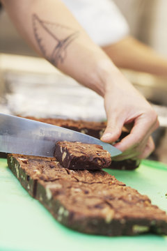 Cropped image of chef cutting brownies at table in restaurant