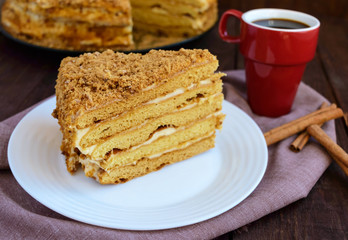 Honey cake and cup of coffee  on a dark wooden background. Cutting a piece. The top view.