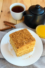 Honey cake and cup of tea on wooden background. Cutting a piece.