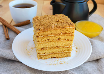 Honey cake and cup of tea on wooden background. Cutting a piece.
