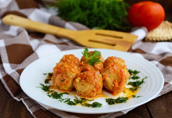 Meat balls on a white plate with greens.
