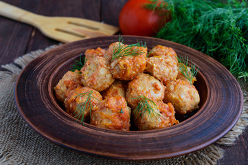 Meat balls with greens in a clay bowl.