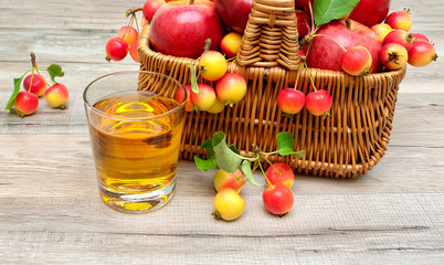 glass of apple juice and ripe apples in a basket