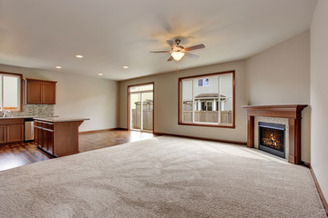 Large empty living room interior with carpet floor and fireplace.